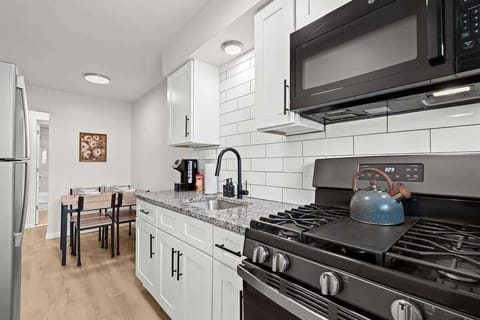 Fully equipped kitchen with granite countertops, stainless steel appliances, and a cozy dining area for four.