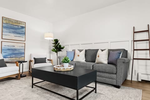 Relax in style in this cozy, modern living room featuring plush seating, chic decor, and calming coastal artwork. Perfect for unwinding after a day of exploring!