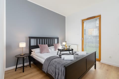 Cozy bedroom with a stylish gray bed and wooden floor, inviting a peaceful night’s sleep.
