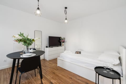 Bright and minimalist living space with a simple bed and a small dining table, providing a calm and inviting atmosphere for guests.
