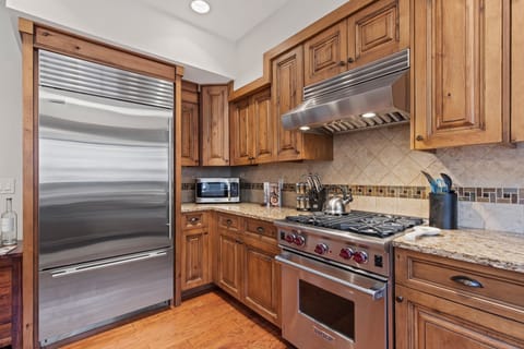 Fully Equipped Kitchen with beautiful stone countertops, stainless steel Wolf appliances, sub zero fridge, and bar seating for 3