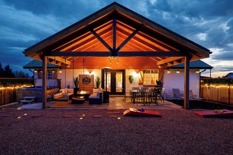 Large patio with a grill, dining area, fire pit, seating, swings, and hot tub