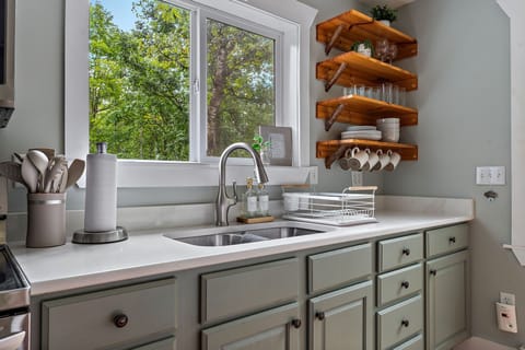 Modern kitchen stocked with essentials (plates, bowls, cups, pots, pans, spices)
