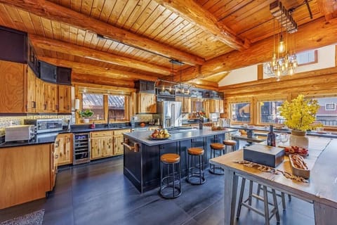 Spacious rustic kitchen with wood beam ceilings, custom cabinetry, and a large central island featuring bar seating and modern appliances.