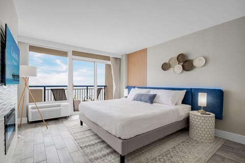Wake up to serene ocean views in this stylish bedroom with floor-to-ceiling windows and a private balcony. Enjoy natural light, a cozy bed, modern fireplace, and sleek TV, blending comfort and luxury. Perfect for a relaxing retreat by the sea.