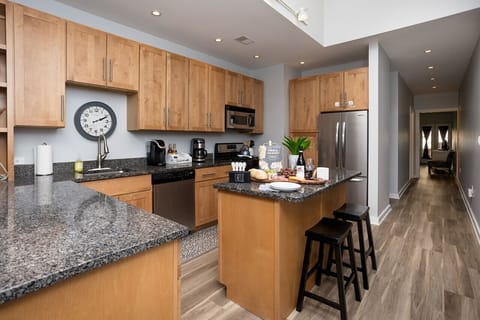 The kitchen connects to the hallway, which leads to the second bathroom and the queen bedroom.