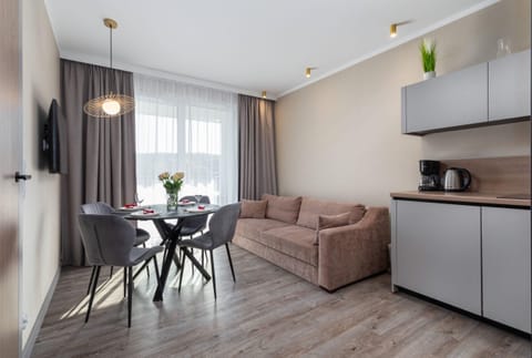 A bright living room with a modern sofa, dining table, and soft lighting, offering a comfortable space to relax.
