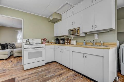 Cook together in this classic white-cabinet kitchen with stove, sink, and long counters—an open setup that keeps you close to the living area while meals come together.