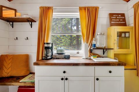 The Cottage has the cutest kitchenette ever! So you want to cook bacon and eggs. Not a problem, the cooktop will make that easy. Brew a cup of tea or coffee, plug the coffee pot into the Jackery (portable generator) and you are ready for a cup of coffee on the front porch. 

There is no running water, a canister is provided for you to wash your hands and clean dishes. A fun and...