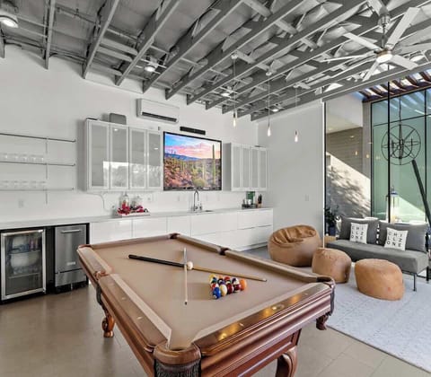 Modern game room featuring a pool table and comfortable seating with natural light.