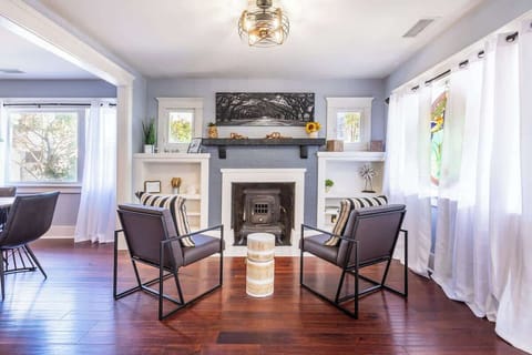 Relax in this beautifully designed living room featuring a modern fireplace, and large windows that fill the space with natural light. The cozy seating area with accent chairs creates a perfect spot to unwind or enjoy a morning coffee. 
