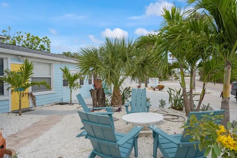 Siesta Key Beach Retreat features a private patio with teal seating, lush tropical palms, and a serene setting ideal for relaxing or entertaining anytime.