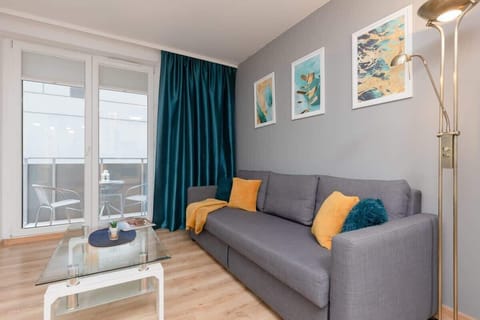 A bright and modern living room with a comfortable gray sofa, turquoise curtains, and a vibrant decor featuring colorful pillows and artwork.