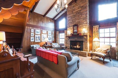 Warm living area with stone fireplace, wooden walls, and cozy seating.