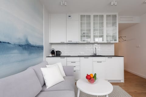 A bright, modern studio with a comfortable bed, a round coffee table, and large windows overlooking the outdoors.