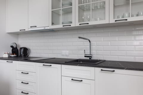 A compact kitchen with white cabinetry, a black countertop, and modern appliances, offering everything you need for cooking.