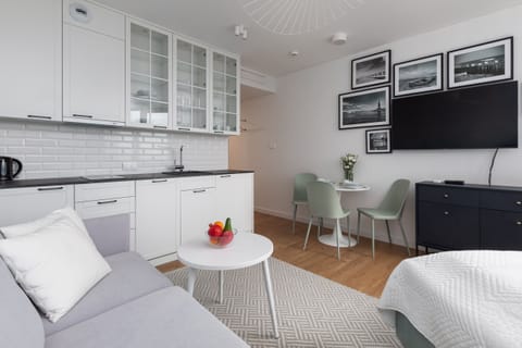 A bright, modern studio with a comfortable bed, a round coffee table, and large windows overlooking the outdoors.