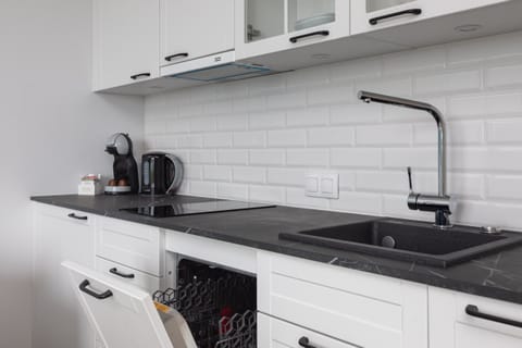 A compact kitchen with white cabinetry, a black countertop, and modern appliances, offering everything you need for cooking.