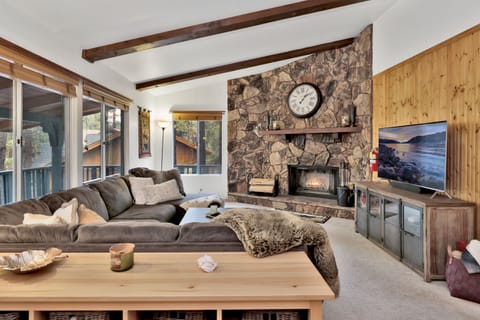Cozy mountain living room with a stone fireplace, comfy seating, and smart TV—perfect for relaxing evenings, movie nights, and warm cabin vibes after outdoor adventures.