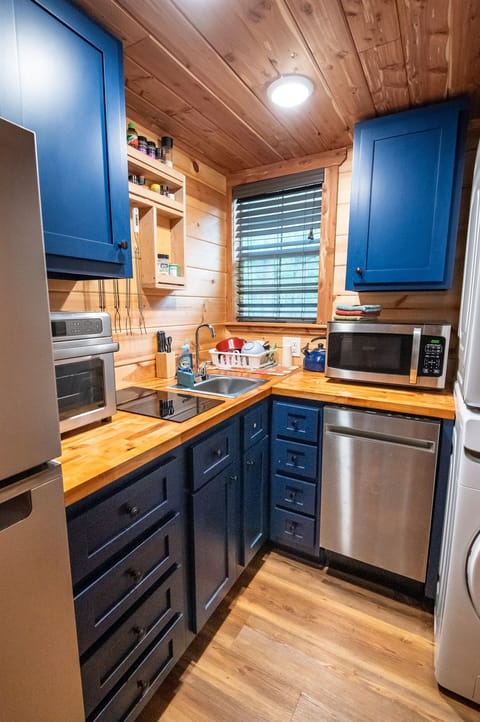 - Bright kitchen with blue cabinets and wood counters   - Organized space with spices and cookware ready   - Perfect for cooking during your forest cabin getaway forest retreat