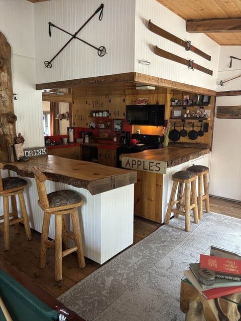 Rustic kitchen and bar area featuring reclaimed wood counters, cozy bar stools, and charming cabin décor with an open, inviting layout.