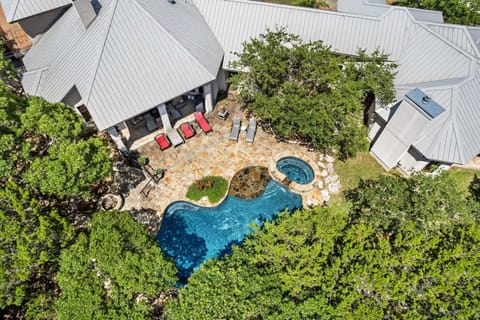 An aerial view showcases this stunning vacation rental, featuring a sparkling pool, a relaxing hot tub, and a spacious patio area, all nestled amidst lush greenery for ultimate privacy and enjoyment.