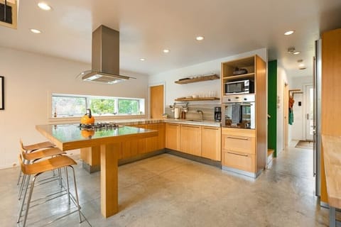 Our open-concept kitchen with oven, gas range,  microwave, coffee maker, bar seating and dining table.