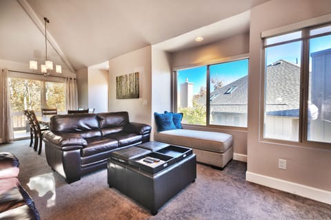- Bright living room with leather seating and ottoman table  
- Large windows with views and cozy lounge nook  
- Open flow design perfect for relaxing and entertaining