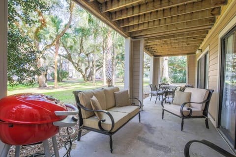The partially covered back patio has a seating area, dining table and garden views.