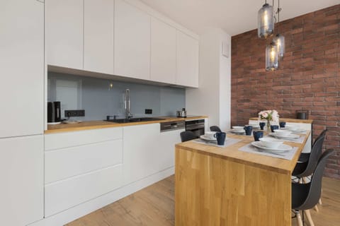 Another angle of the kitchen with a view of the white cabinets, wooden countertop, and contemporary lighting fixtures.