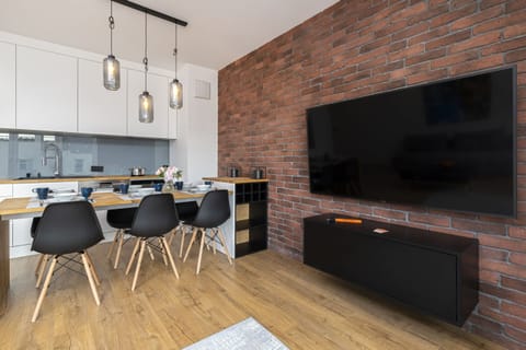 A modern kitchen with white cabinetry, a wooden island, and black chairs around the dining table.