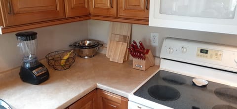 Glass cook top with plenty of cookware in lower left corner cabinet