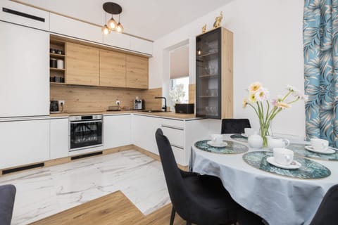 A fully equipped kitchen with white cabinets, wooden accents, and a minimalist design.
