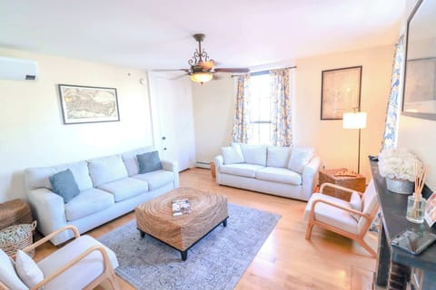 Living Room has plenty of seating, tall windows overlooking the West End, and historic fireplace detail.
