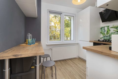 A compact dining area with a wooden counter and stools, complemented by a scenic view through a window.
