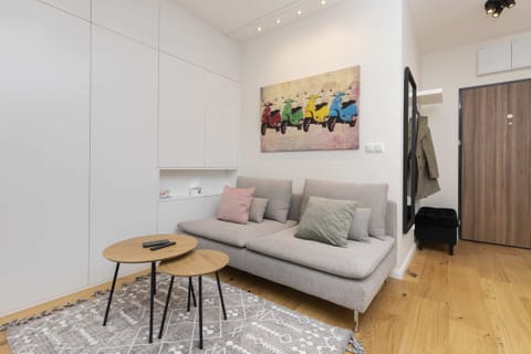 A modern living room with a light sofa, colorful artwork, and a cozy rug.
