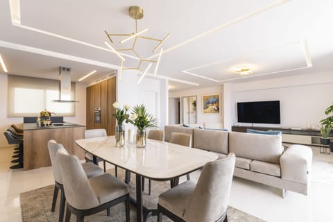 The modern open-plan living space includes a dining area and a Smart TV.