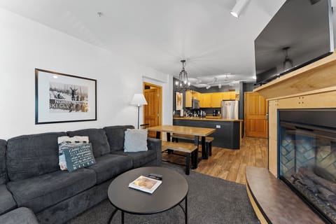 Unwind in your cozy living space with plush seating, warm fireplace, and open kitchen perfect for relaxing evenings.