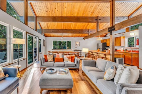 Living Room: 2 couches, 1 chair, wood-burning fireplace, 55” Smart TV, access to deck
