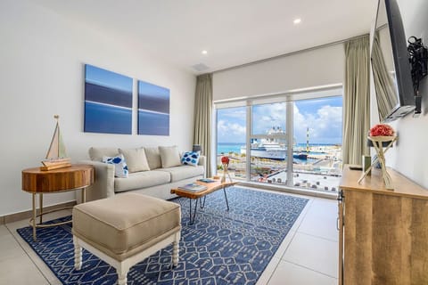 Stunning waterfront views greet you from this bright, coastal-inspired living room. Relax on plush seating while watching cruise ships glide by through floor-to-ceiling windows.