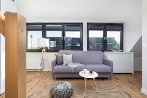 A bright living room with a modern sofa, coffee table, and a view of large windows.
