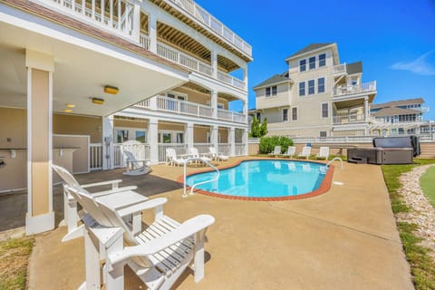 Soak up the sun by your private pool, surrounded by white Adirondack chairs and a covered patio—your perfect retreat for morning coffee or afternoon relaxation under clear blue skies.