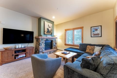 Cozy up in your spacious living room featuring plush seating, stone fireplace, and entertainment center for memorable mountain evenings.