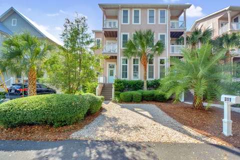St. Simons Vacation Rental – Townhome Exterior & Driveway - Front view of a three-story St. Simons Island vacation rental with lush palm trees, private driveway, and charming coastal architecture—just one block from the beach and restaurants.