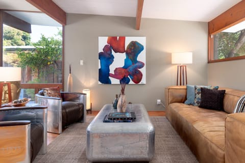 The first room upon entering is the living area, with high-end furnishings, some of them inspired by the luxury Airstream trailer brand.  Note the wooden beams in the ceiling, which are typical of homes designed and built by Joseph Eichler.
