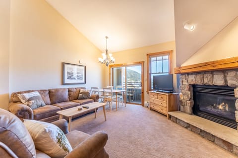 Cozy up by your crackling stone fireplace while mountain views frame your peaceful living space through floor-to-ceiling windows.
