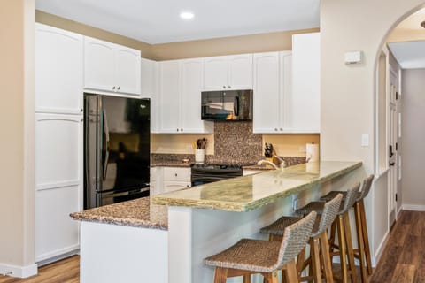 Full kitchen with breakfast bar, granite counters, and modern appliances