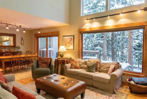 This charming home's bright and open living room features high ceilings and spacious windows perfect for watching the snowfall or enjoying the nature views as you relax by the fire.