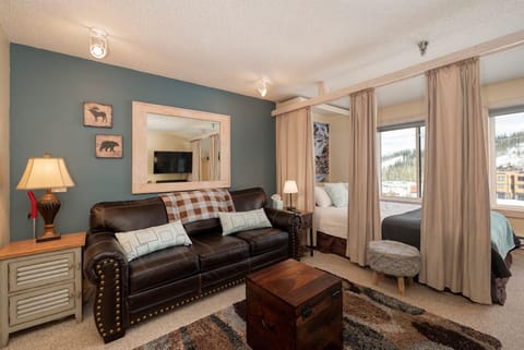Your cozy mountain retreat combines rustic charm with modern comfort, featuring a plush leather sofa and stunning slope views.