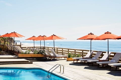Lounge oceanfront under vibrant umbrellas, listening to waves.